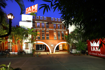 Front view of IAM campus at night, showcasing infrastructure of the best hotel management institute in India with clear branding.