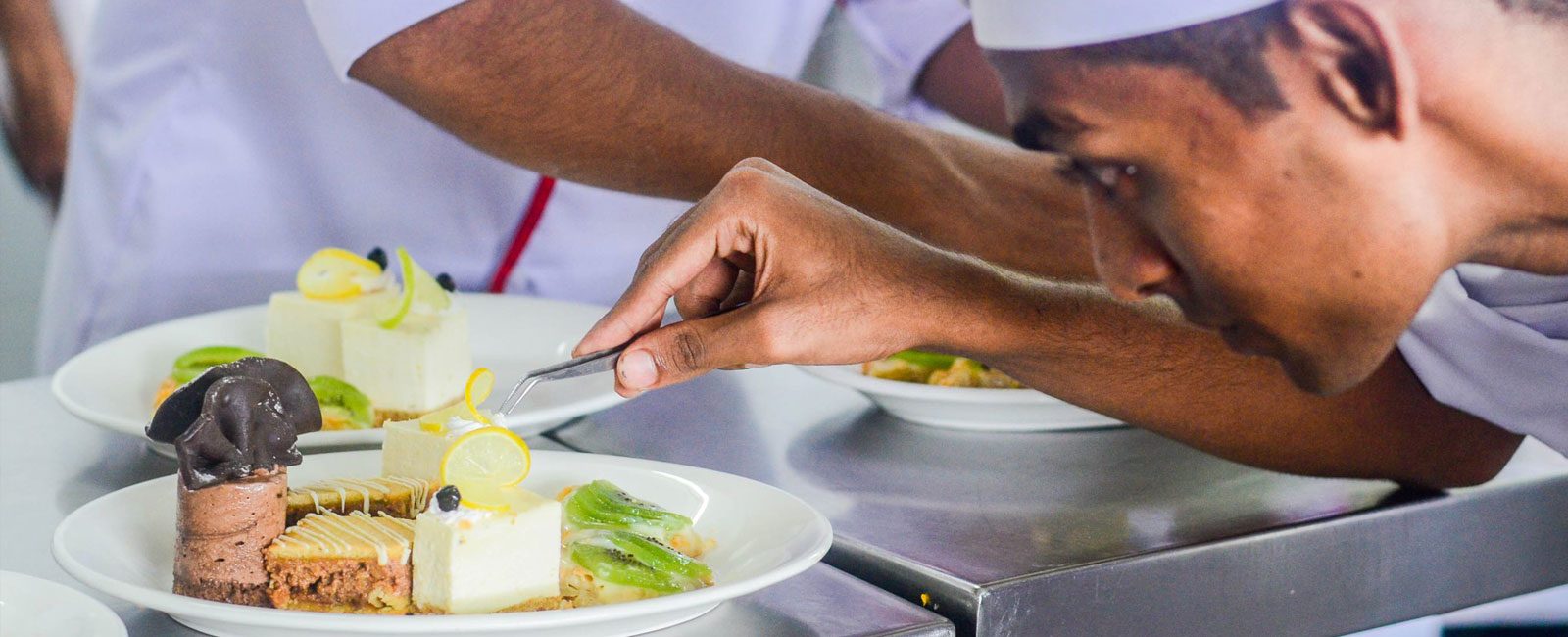 IAM student carefully garnishing dessert as part of practical training under professional hotel management courses.