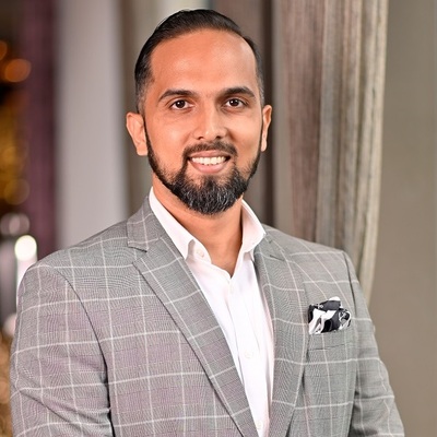 Our Industry Expert Arjun Kaggallu, representing the best hotel management institute, dressed in a grey checkered suit.